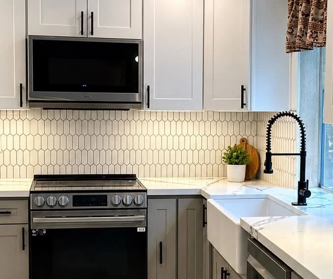 Kitchen backsplash with elongated hexagon tiles, white cabinets and black fixtures